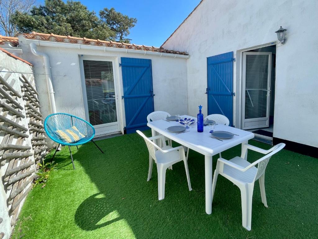 une table et des chaises blanches sur une cour avec de l'herbe dans l'établissement Maison T3 à 800 m de la plage avec piscine chauffée, tennis, Wi-Fi, patio clos et parking privatif - FR-1-231-300, à Bretignolles-sur-Mer