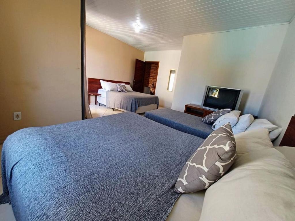 a hotel room with two beds and a television at Casa com 3 suítes em Cabo Frio com piscina há poucos passos do Mar! in Cabo Frio