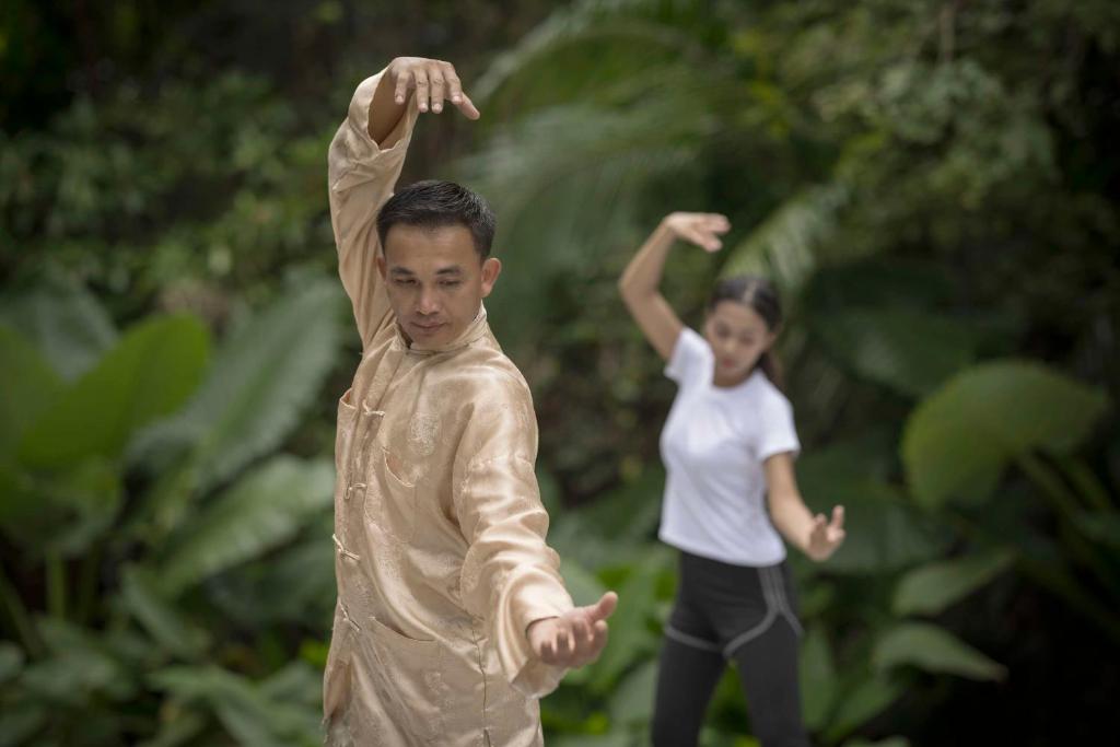 a boy and a girl standing in front of a statue at Banyan Tree Samui in Lamai