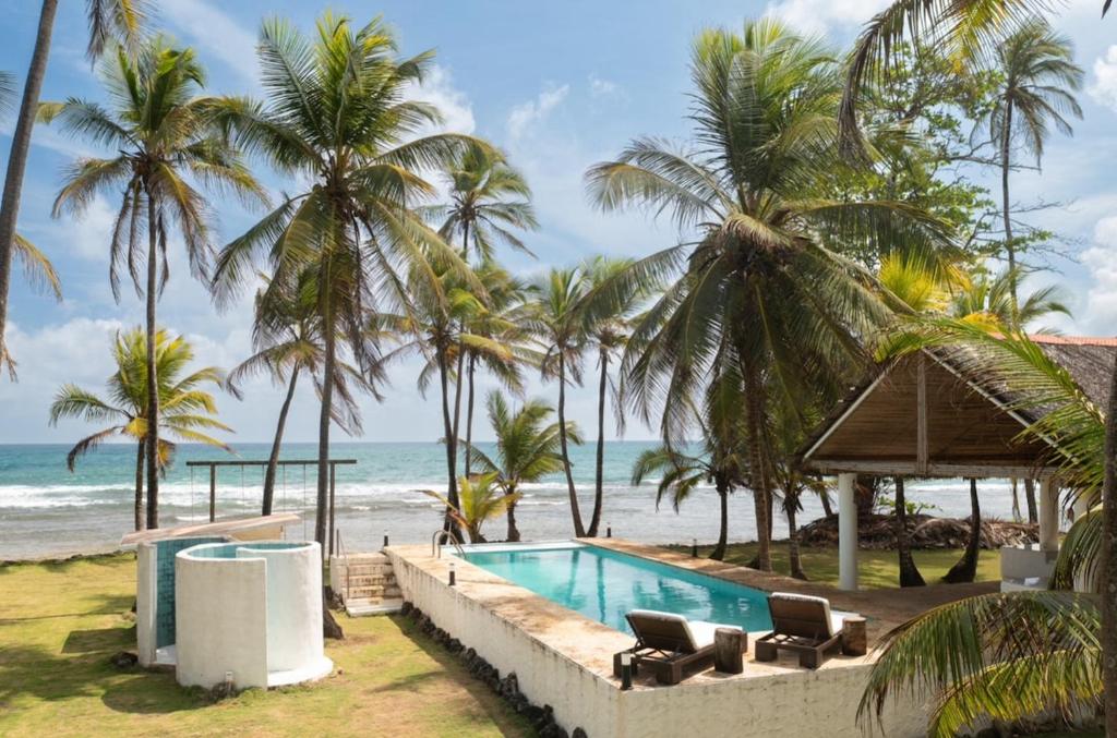 a swimming pool next to a beach with palm trees at Beachfront Property in Palenque - Paradise! in Palenque