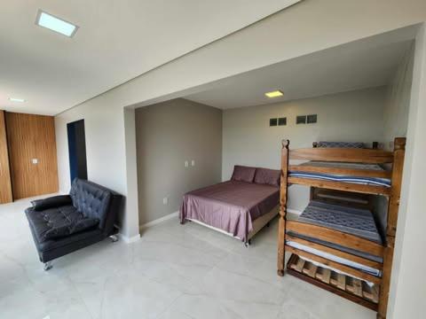 una camera da letto con un letto a castello e una sedia di Apartamento - 4 pé na areia proximo a lagoa e rio a Passo de Torres