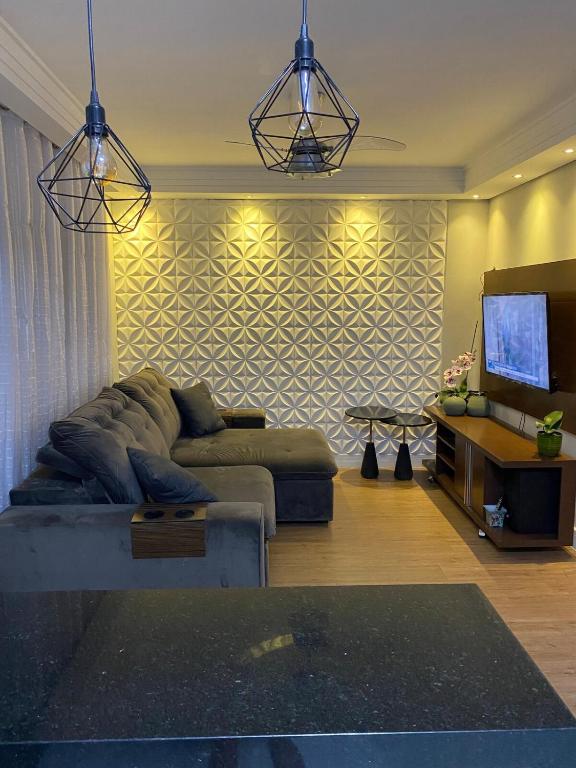a living room with a couch and a flat screen tv at Apartamento Maitinga aconchegante in Bertioga