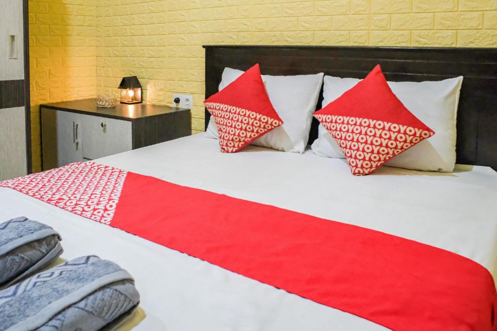 a bed with red and white pillows on it at OYO 93333 Rama Home Stay in Jayapura