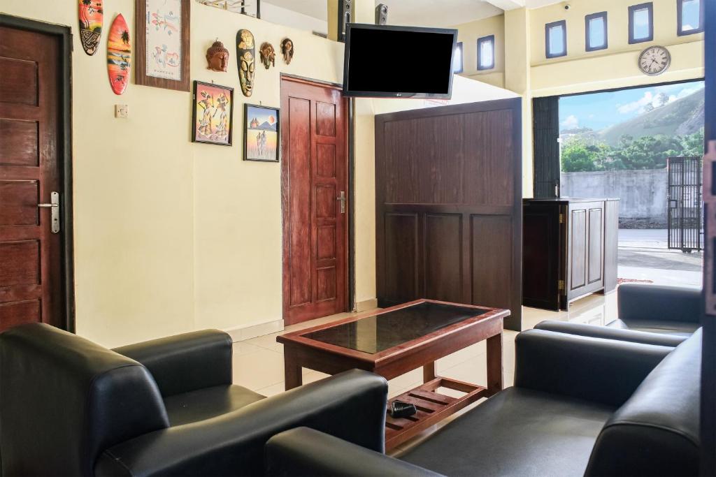 a waiting room with chairs and a table and a tv at OYO 93332 Kharis Home Stay in Jayapura