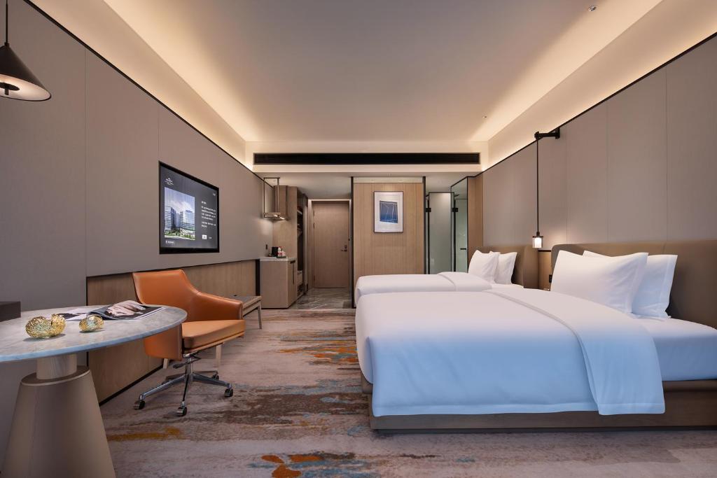 a hotel room with two beds and a desk at voco Changsha Airport by IHG in Changsha
