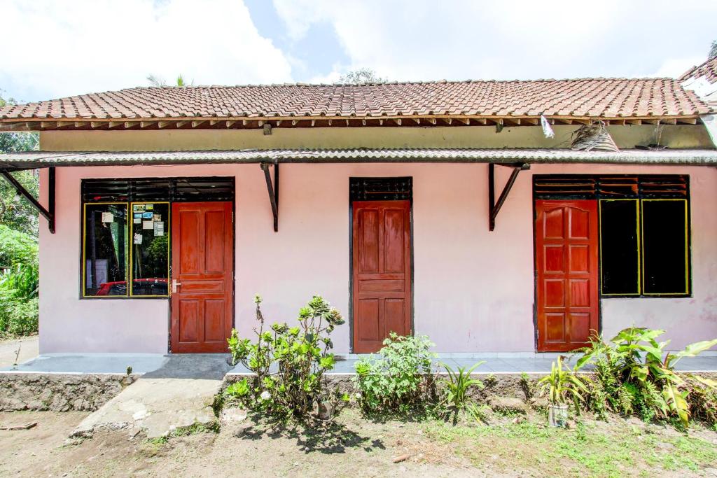 a small white house with red doors at Hotel O Pondok Wisata Sekar KemuningNearWonogondang Camp ( Bumi Perkemahan Wonogondang ) in Yogyakarta