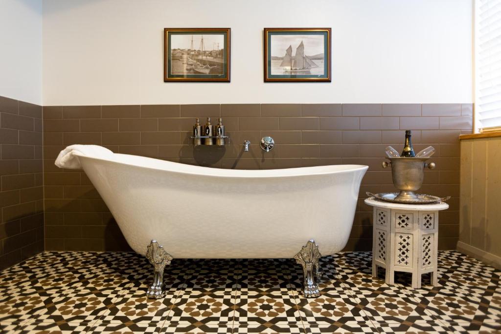 a bath tub in a bathroom with green tiles at The Rivulet in Hobart