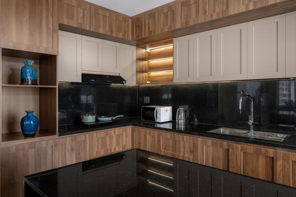 A compact corner kitchen with black stone counters, appliances and wood cabinetry.