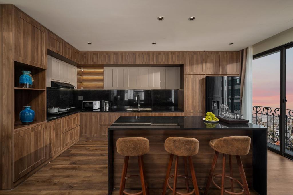 A full kitchenette with a breakfast island, three stools and a balcony-side window.