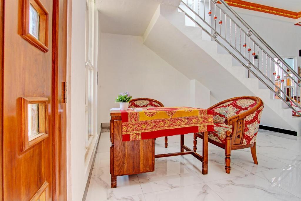 a table with two chairs in a hallway with stairs at Hotel O Muula Homestay Syariah in Pati