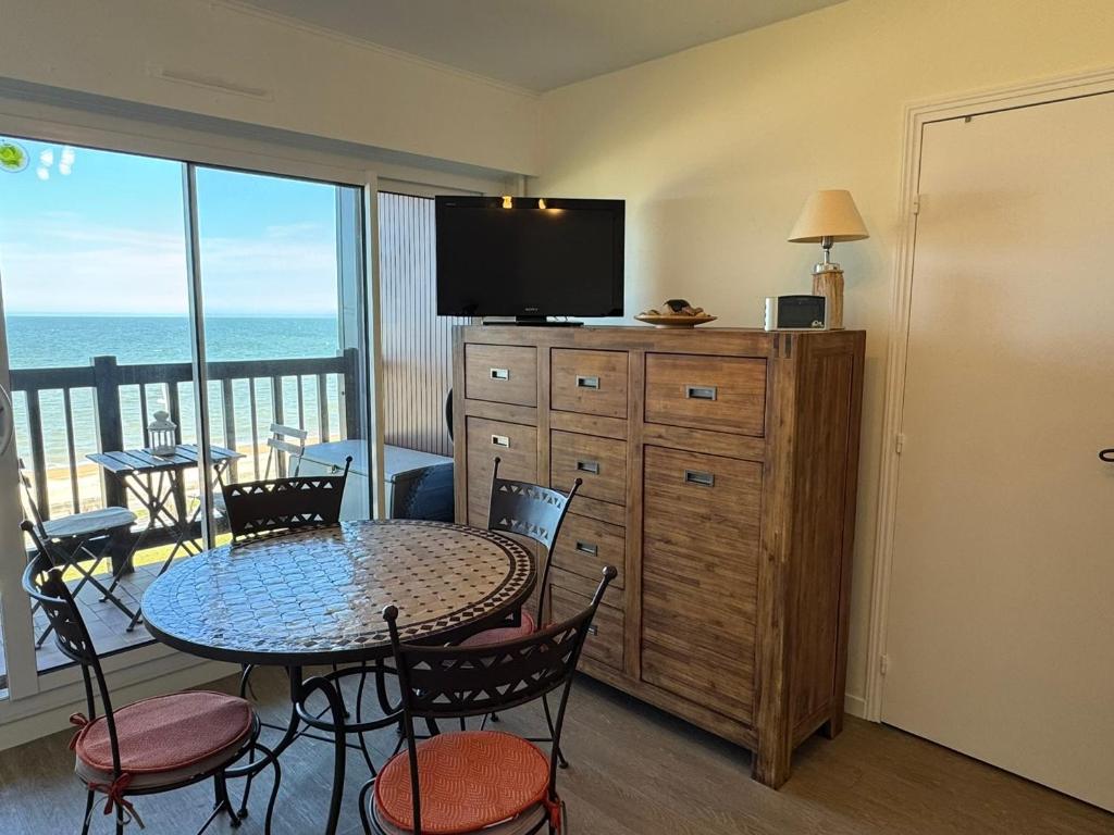 une pièce avec une table, des chaises et une télévision dans l'établissement Studio en bord de mer avec balcon et vue imprenable, accès direct plage - FR-1-487-317, à Cabourg