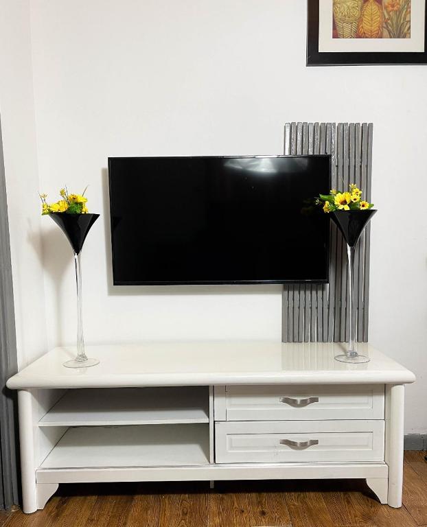 a white entertainment center with two vases and a flat screen tv at Woods Cottage Kilimani in Nairobi