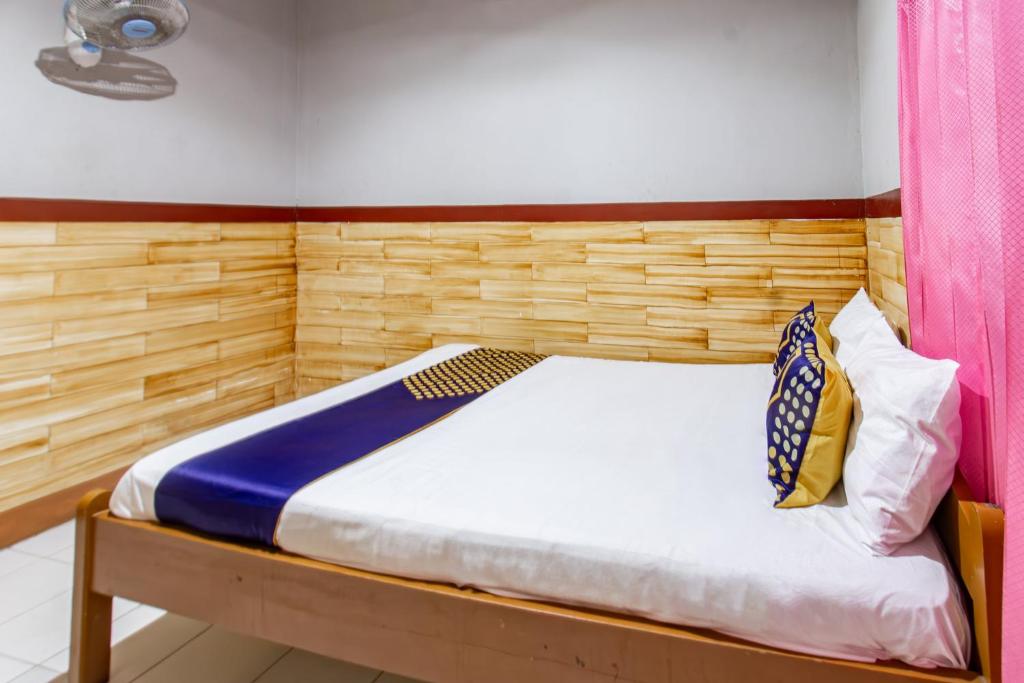 a bedroom with a bed with a wooden headboard at Hotel O De Lanang Homestay Near Masjid Janapria in Papak