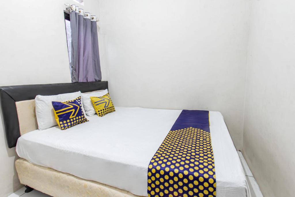 a bed with yellow and blue pillows in a room at Hotel O Penginapan Melati Tanjung Near Kantor Pengamat Pengairan Tanjung in Papak