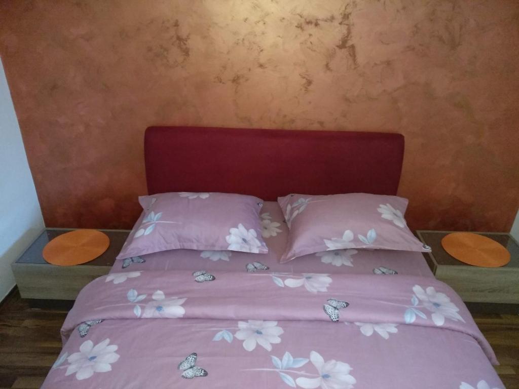 a bed with pink sheets and white flowers on it at Apartments Popovic in Podgorica