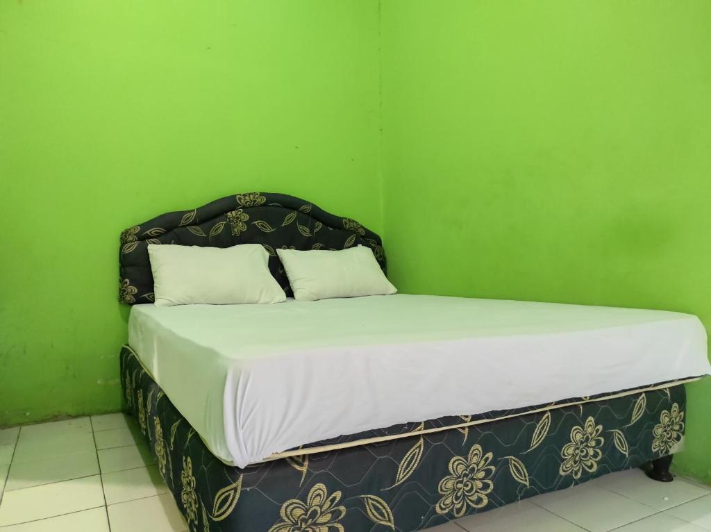 a bed in a room with a green wall at OYO 93411 Syariah Hotel Tomborang in Karema