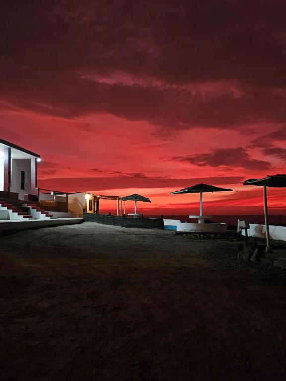 a group of umbrellas on the beach at sunset at Hotel Za'Warmi in Huarmey
