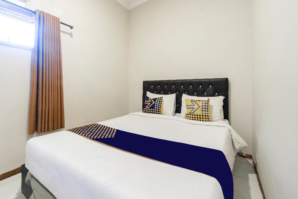 ein Schlafzimmer mit einem Bett mit blau-weißer Bettwäsche in der Unterkunft Hotel O Triple N Homestay in Sidoarjo
