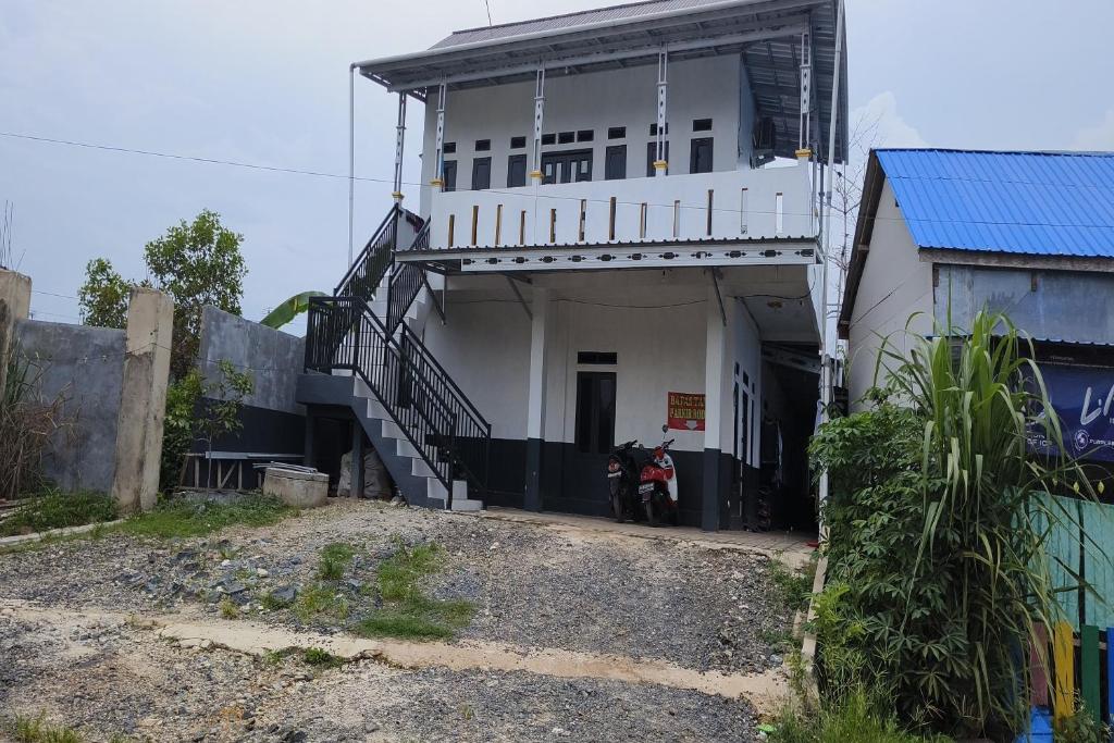 a white building with a motorcycle parked in front of it at Hotel O Penginapan Al-asharNearWarung Acil Ubai in Rantau