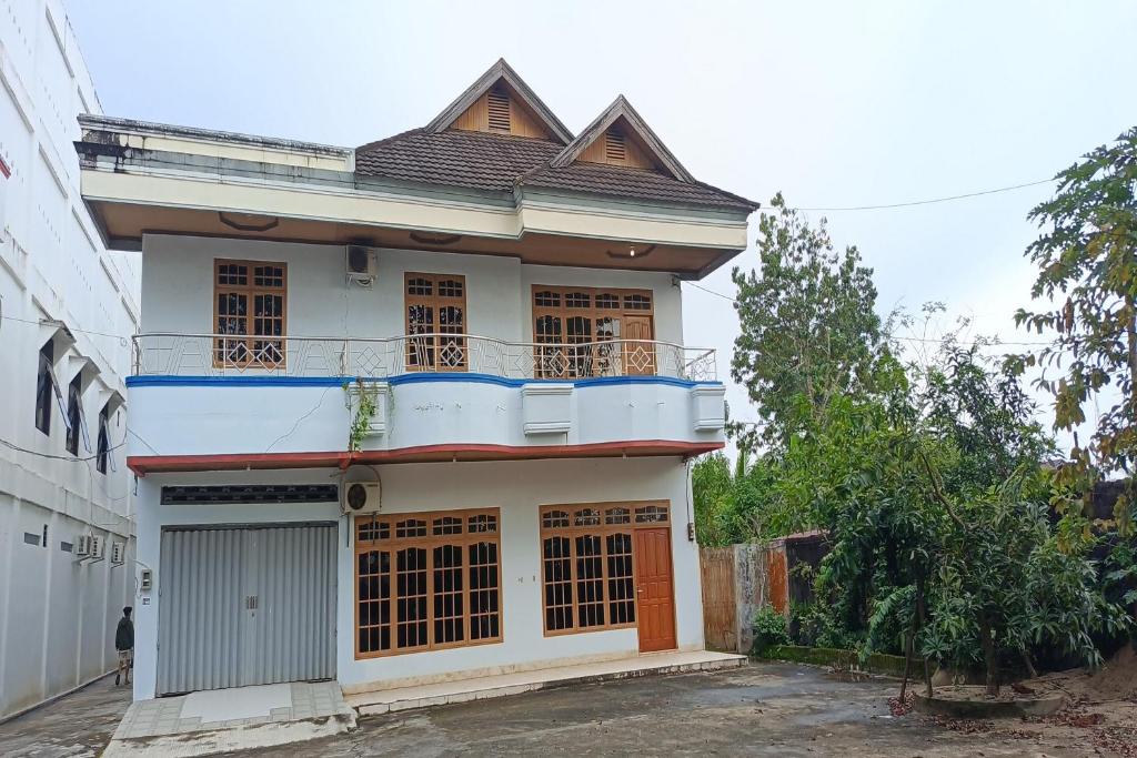 a white house with a balcony on top of it at Hotel O Karunia Kost & PenginapanNearSiring Marabahan (Ulek Barito) in Sungaisalai