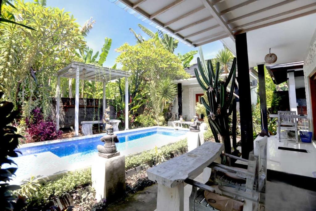 ein Pool mit einer Bank neben einem Haus in der Unterkunft Belvilla Ananda Resort Lovina BeachNearPantai Lovina in Lovina