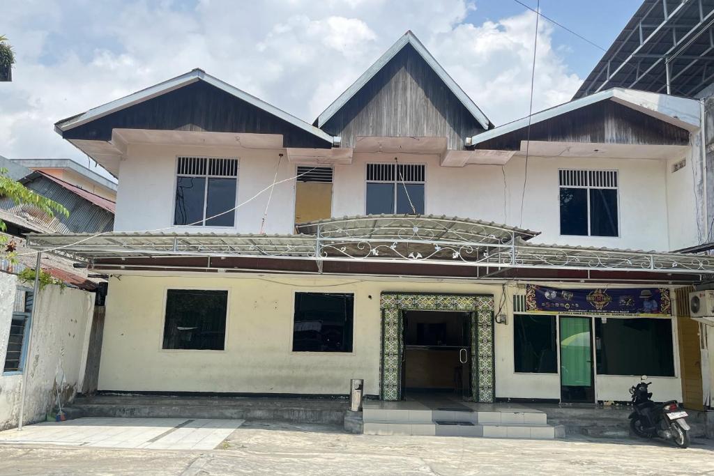 a building with a motorcycle parked in front of it at Hotel O Aglo Homestay NearYani Heahlerr in Rantau
