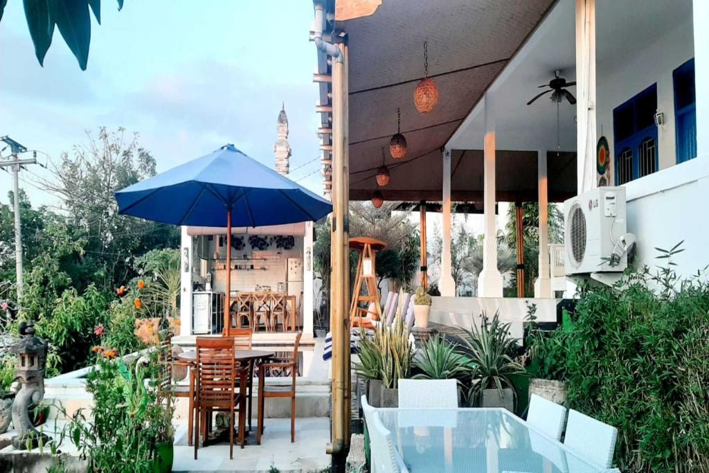 a patio with a table and a blue umbrella at Belvilla Tranquil Oasis Lovina BeachNearKrisna Funtasticland in Lovina