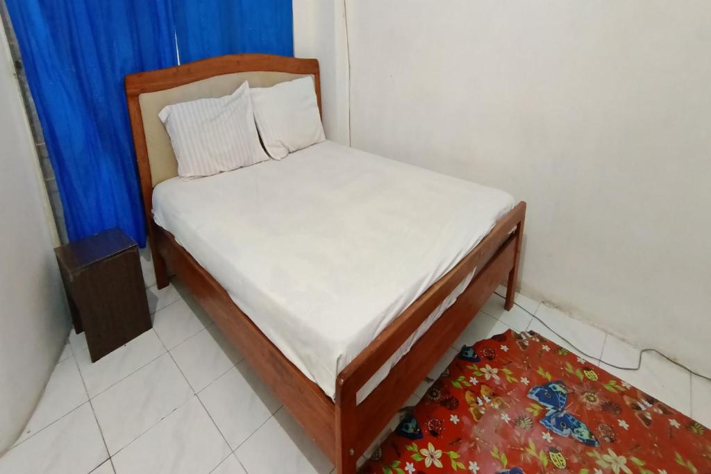 a small bed in a room with a blue curtain at Hotel O Pondok Bintang in Kendari
