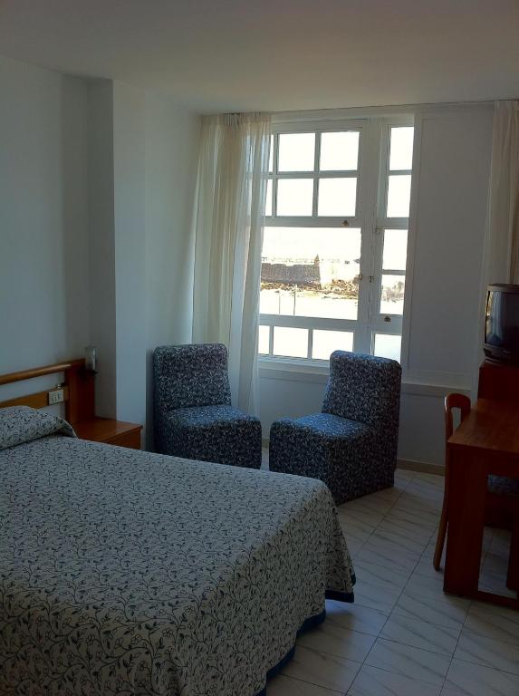 sypialnia z łóżkiem, 2 krzesłami i oknem w obiekcie Hotel Pinzon w mieście Baiona