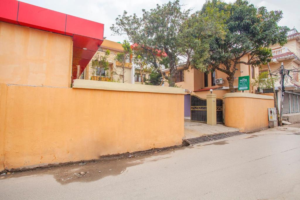 an empty street with a yellow wall and trees at OYO 817 Hotel Garden Flower in Kathmandu