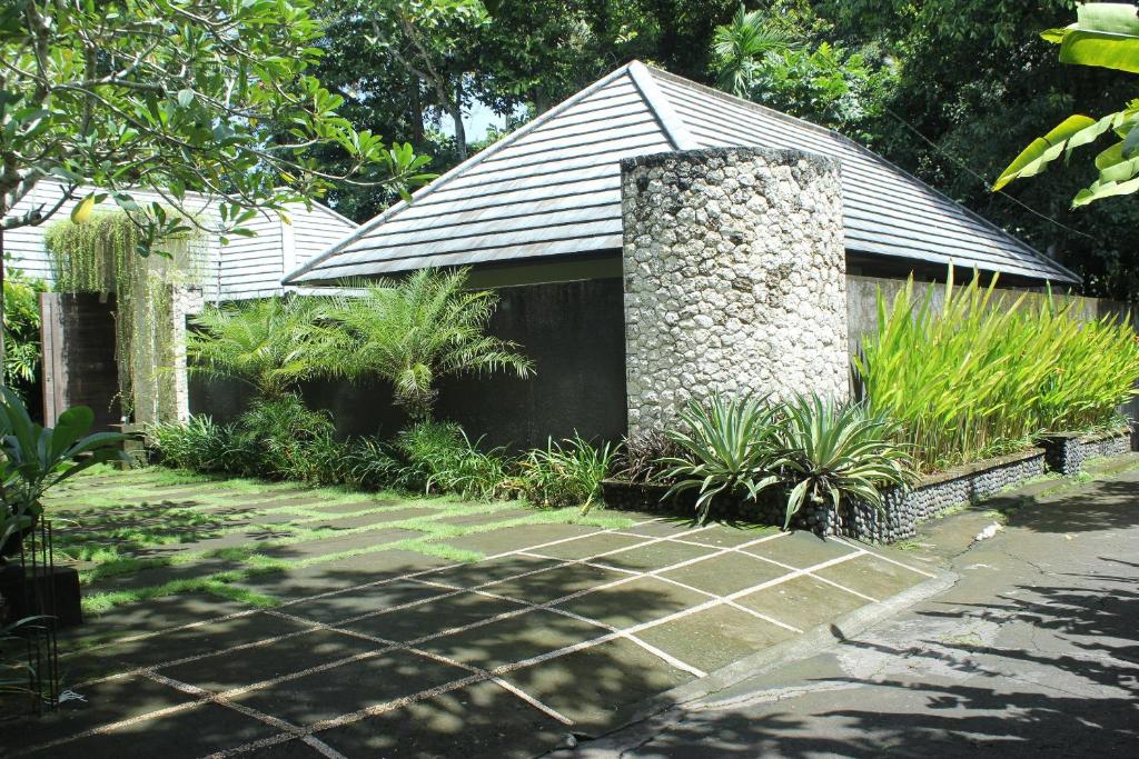a house with a stone pillar in a garden at Belvilla Dhyana Kutir Seseh Beach in Munggu
