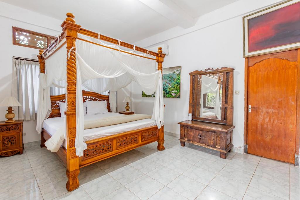 a bedroom with a canopy bed and a mirror at Belvilla Ratna Resort Ubud PalaceNearUbud Palace in Ubud