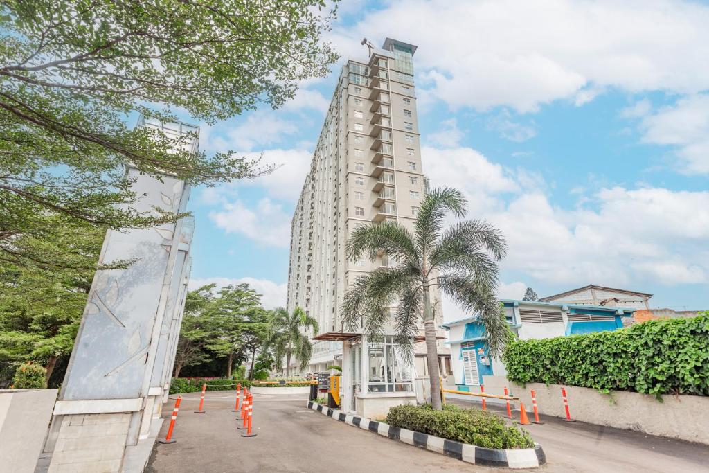 a tall white building with a palm tree in front of it at OYO 94010 Victoria Square in Kandang-besar