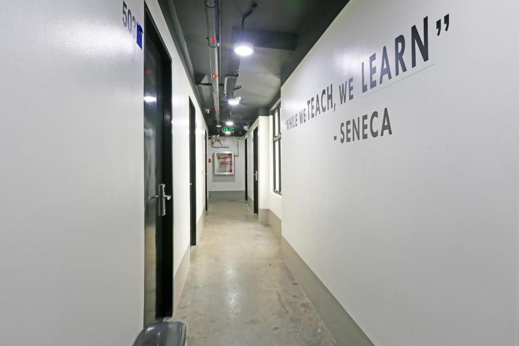 um longo corredor com uma parede branca com escrita nele em Spot On Classy Bunkbeds Near Makati Manila Formerly MYTOWN Madrid em Manilla