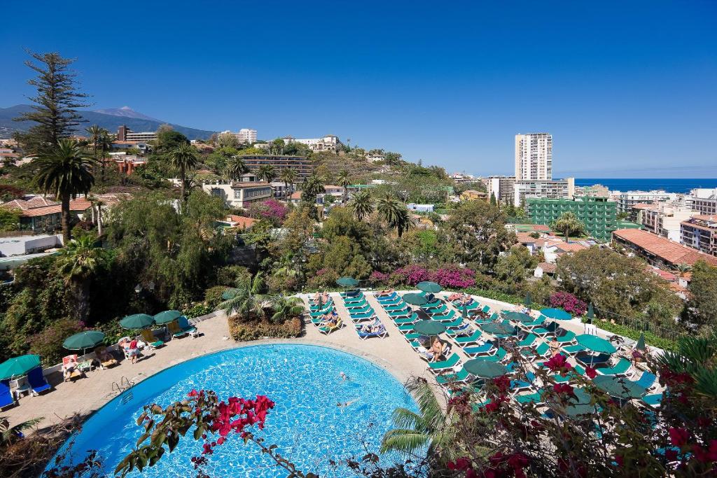 a large pool with chairs and umbrellas on a beach at Hotel Atlantic El Tope in Puerto de la Cruz