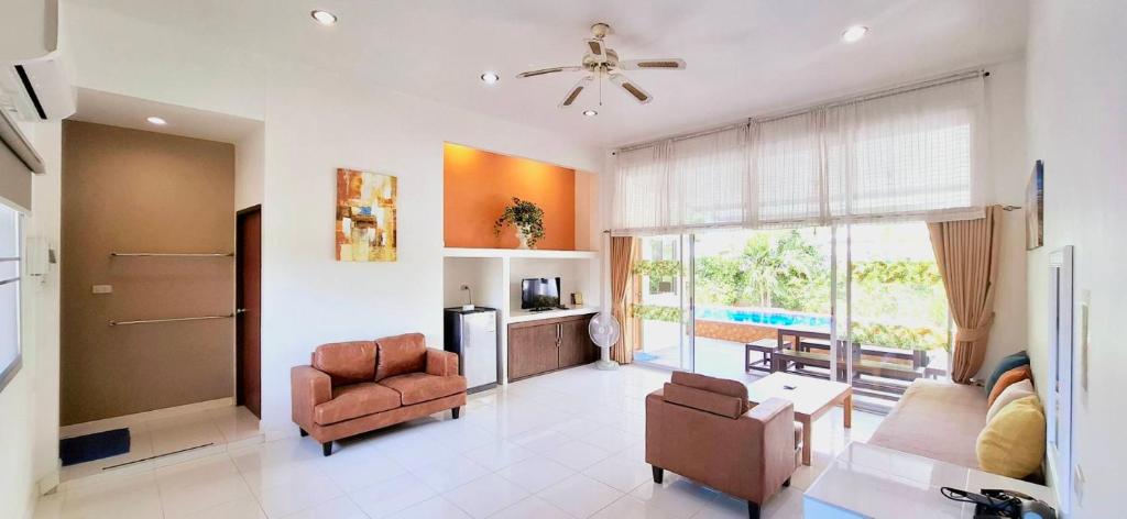 een woonkamer met een bank en stoelen en een raam bij Baan Pare in Pran Buri