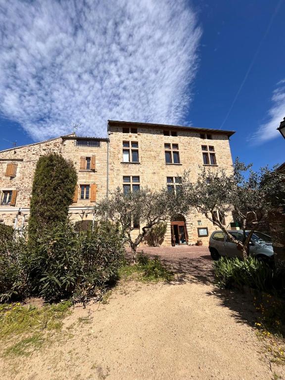 un grand bâtiment en briques avec une voiture garée devant. dans l'établissement auberge des trois ami-es, à Vinezac