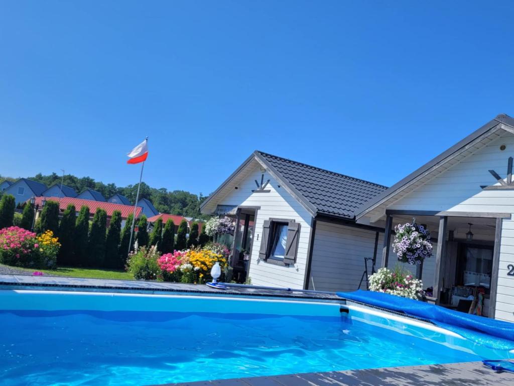 a house with a swimming pool in front of a house at Białe Domki in Sarbinowo