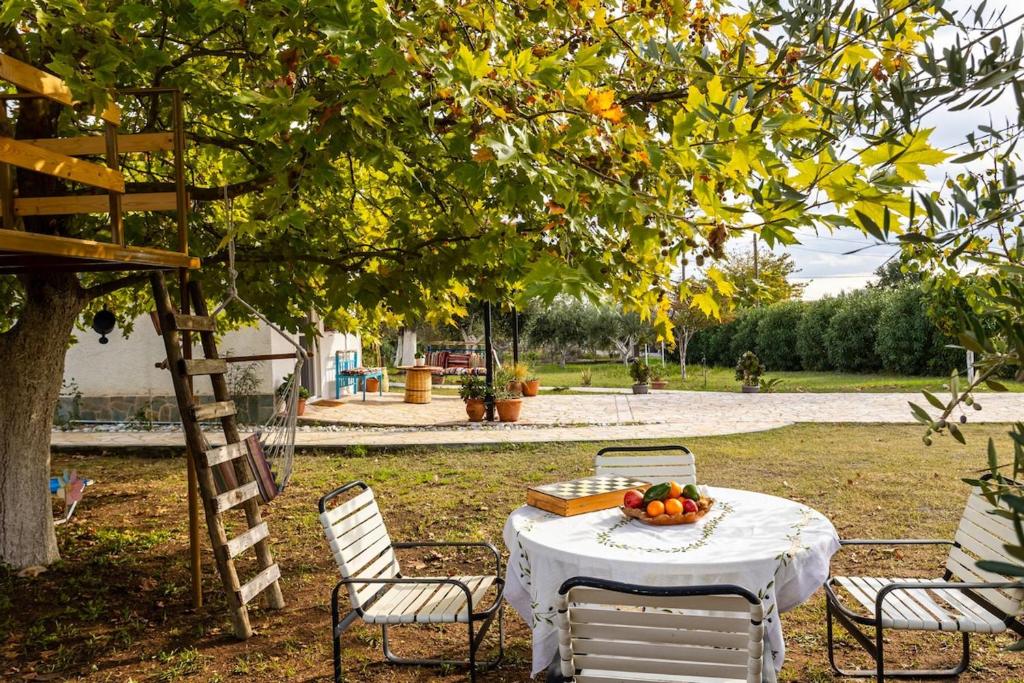 a table with a bowl of fruit on it under a tree at Petalidi Sunny Home Two - Cozy Garden Escape in Petalidi