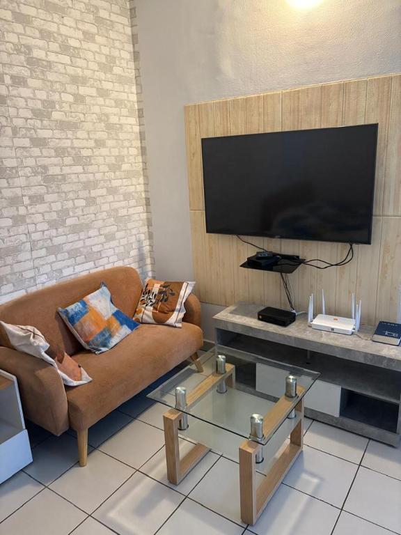 un soggiorno con divano e TV a schermo piatto di Sipim aéroport a Abidjan