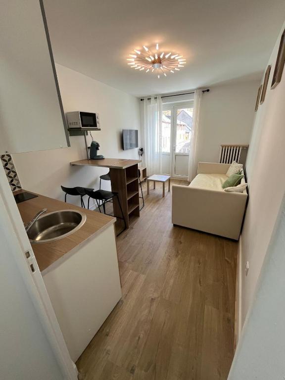 Il dispose d'une cuisine et d'un salon avec un évier et un canapé. dans l'établissement Les balcons du 115 - appartement standing 4 étoiles, à La Bourboule