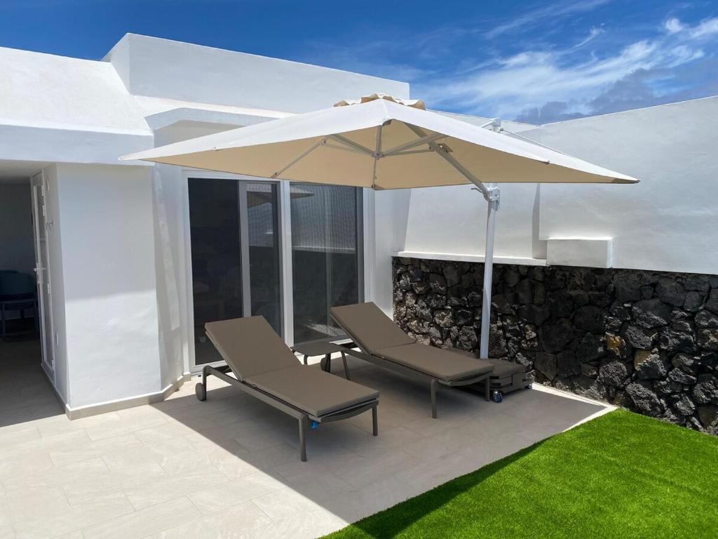 a patio with two chairs and an umbrella at VV Sal y Mar Apartment in Los Cancajos
