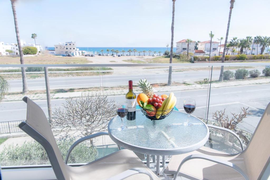 una mesa con un bol de fruta y una botella de vino en Themis Beach Apartments, en Lárnaca