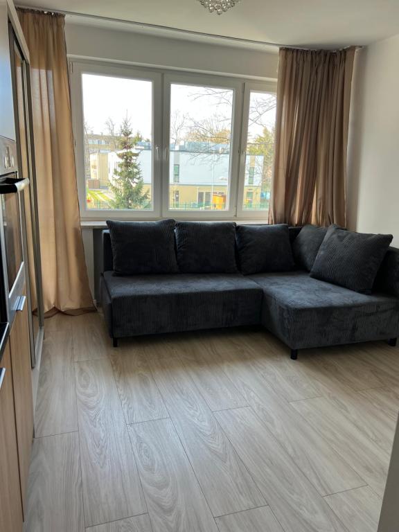 ein Wohnzimmer mit einer blauen Couch vor Fenstern in der Unterkunft Studio apartment&Airport- free WiFi - Netflix - close by Chopin Airport in Warschau