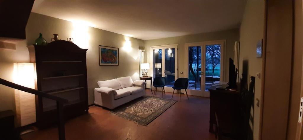 a living room with a white couch and a chair at Il Fienile, casa vacanza in campagna con parcheggio privato e giardino privato, a 6 chilometri da Bologna centro e 1 chilometro da Bologna Fiera, Parco commerciale Meraville e Gran Tour Italia in Bologna