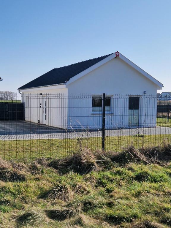 ein weißes Gebäude mit einem Zaun auf einem Feld in der Unterkunft Haus Noah in Sierosław