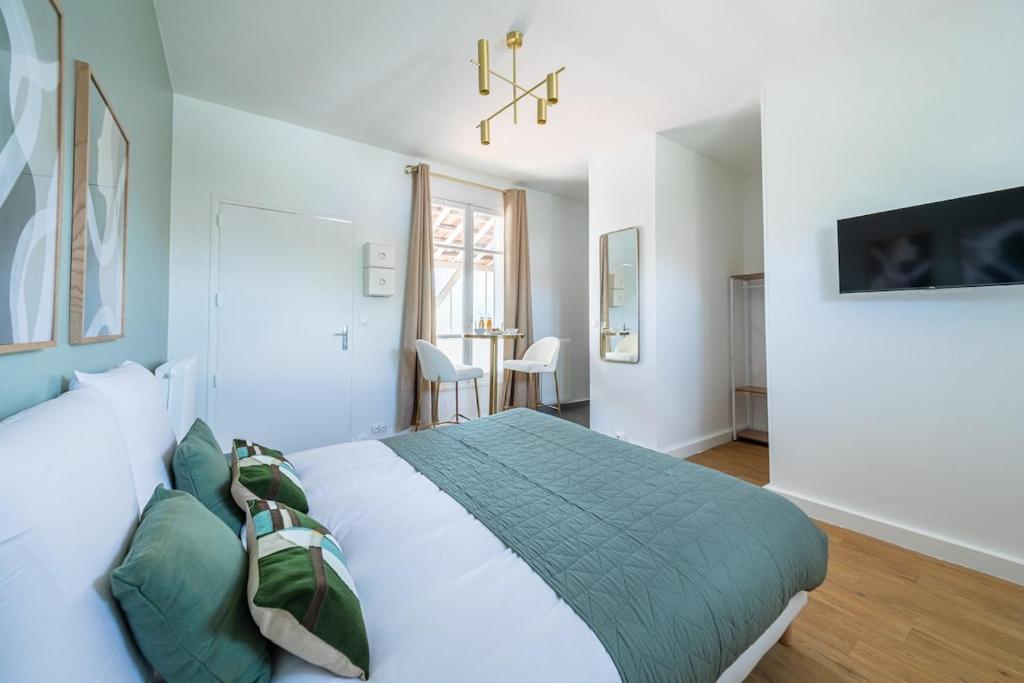 une chambre avec un grand lit blanc avec des oreillers verts dans l'établissement Studio coloré Entre Versailleset Paris- III, à Issy-les-Moulineaux