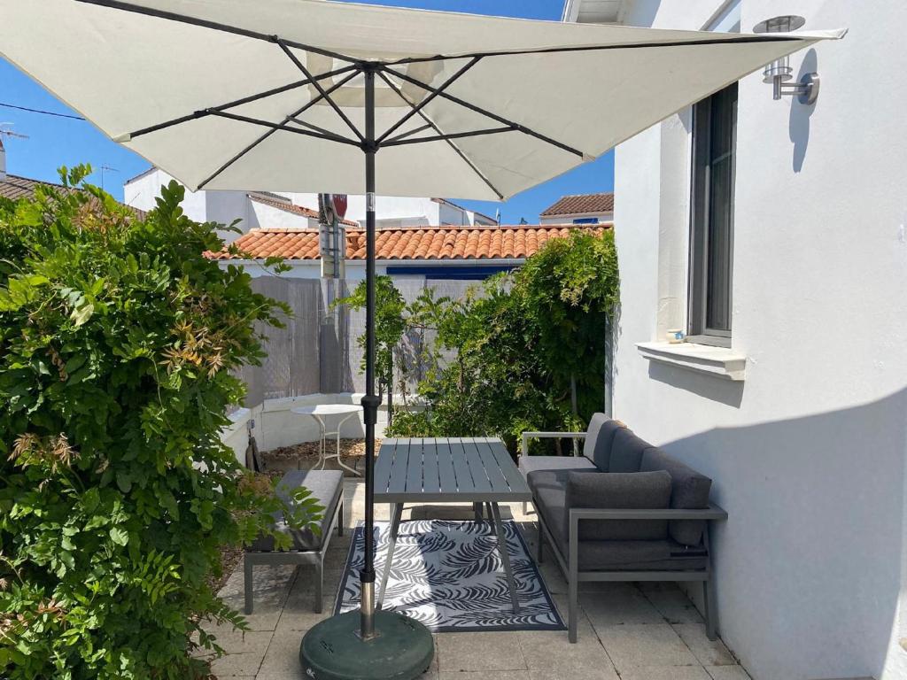 - une table avec un parasol sur la terrasse dans l'établissement Jolie villa en bord de mer avec wifi, à La Tranche-sur-Mer