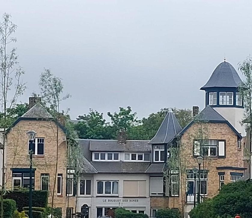 un grande edificio in mattoni con una torre sopra di Centraal appartement met tuintje, vlak bij zee a De Panne