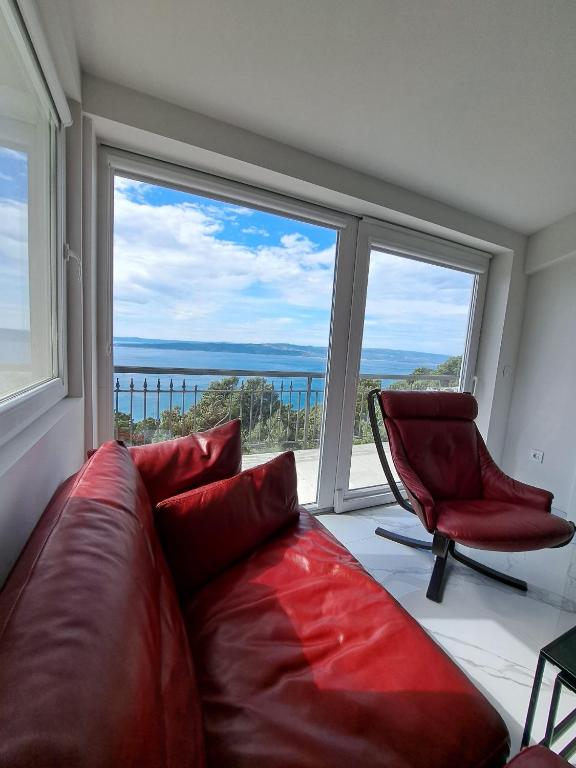 a living room with a red couch and a chair at Apartman SIX in Brela